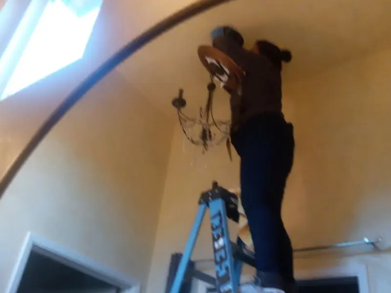 Electrician installing a chandelier in a California residence